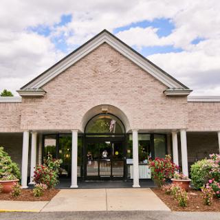 A welcoming entrance of a brick building surrounded by landscaped greenery.
