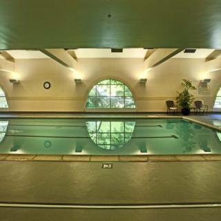 An indoor swimming pool with elegant lighting and large circular windows.