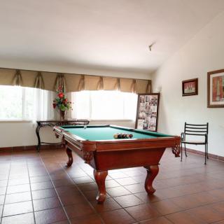 A recreation room featuring a pool table with large windows and tiled flooring.
