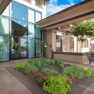 The entrance of a hotel with modern architecture and landscaped greenery.