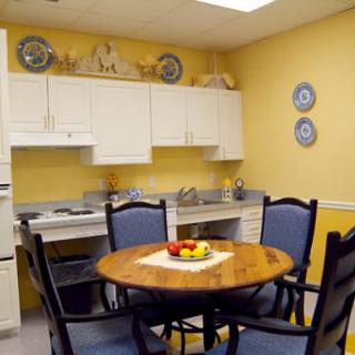 A cozy kitchen with a wooden dining table, surrounded by chairs and decorated with decorative plates on yellow walls.