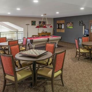A cozy game room featuring a billiards table and multiple seating areas with warm lighting.