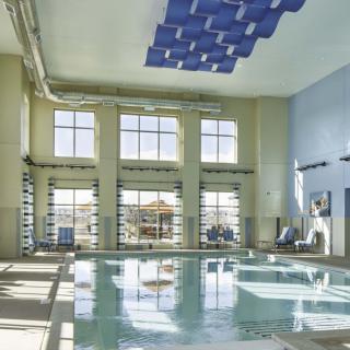 A modern indoor swimming pool with large windows allowing natural light to flood the space.