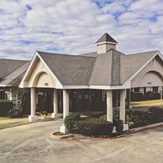 A welcoming residential building with a distinct architectural style, set against a cloudy sky.