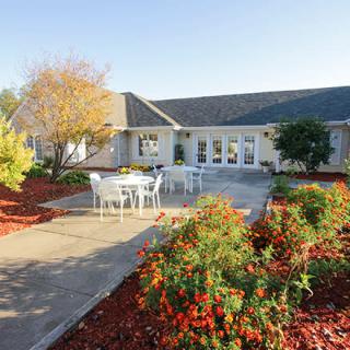 A view of a building with a landscaped garden and outdoor patio seating.