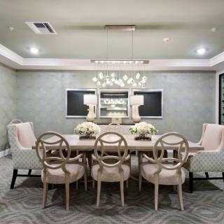 A modern and elegant dining room featuring a stylish chandelier, upholstered chairs, and a large dining table.