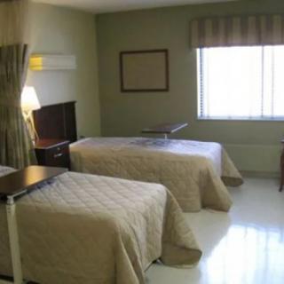 A tidy hospital room featuring two neatly made beds with a window providing natural light.