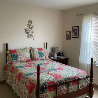 A cozy bedroom with a colorful quilt on a wooden bed frame and soft natural light filtering through the window.