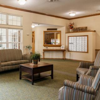 A cozy lobby featuring sofas, chairs, and a coffee table with potted plants.