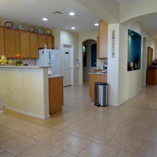 A modern kitchen with wooden cabinets and tiled flooring, featuring an open layout.