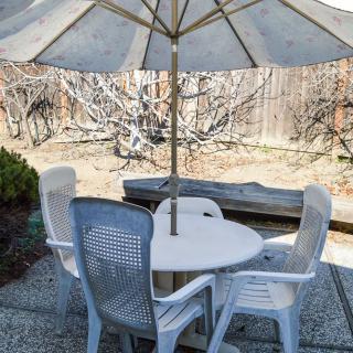 A patio set in a backyard, featuring a round table with four chairs and an umbrella.