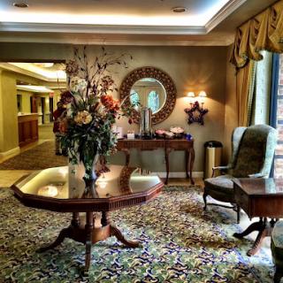 A beautifully arranged lobby featuring elegant furniture, a floral centerpiece, and warm lighting.