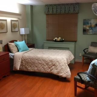 A cozy bedroom with a single bed, warm lighting, and elegant decor on a wooden floor.