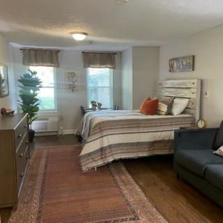 A cozy and well-decorated bedroom with a bed, sofa, and wooden flooring.