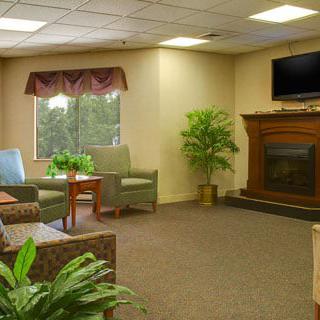 A cozy waiting room with comfortable seating, a television, and a fireplace.