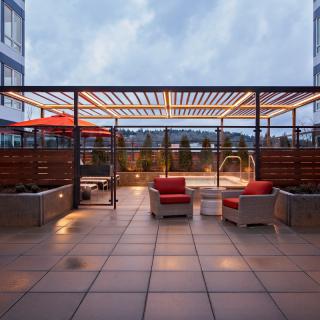 A modern outdoor patio with seating, ambient lighting, and a pergola at dusk.