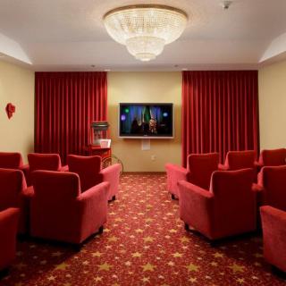 A cozy home theater with red upholstered chairs, a large screen, and elegant lighting.