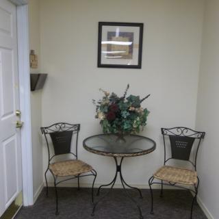 A cozy corner with two chairs, a small round table, and decorative plants.