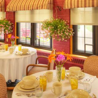 A cozy dining room with elegantly set tables, adorned with flowers and bathed in natural light.