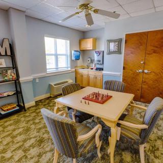 A cozy living room with a chessboard on the table and a bookshelf nearby.