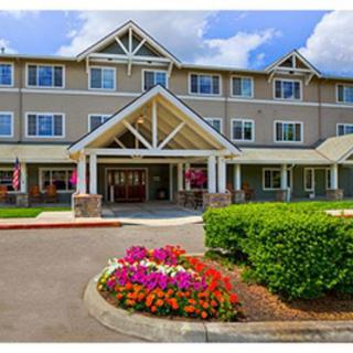A residential building entrance with colorful flower beds and landscaping.