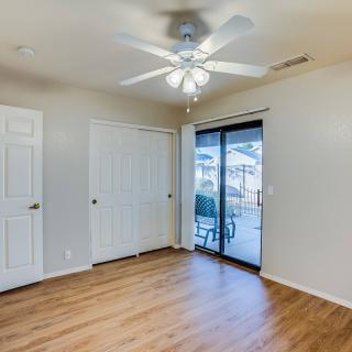 An empty room with wood flooring, a ceiling fan, and sliding glass doors leading outside.
