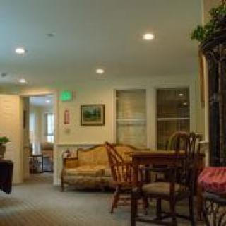 A cozy interior room with seating and a table, featuring warm lighting and homey decor.