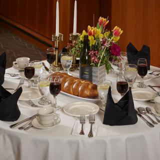 A formal dining table set with candles, flowers, and wine glasses.