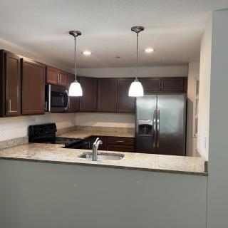 A modern kitchen with brown cabinets and stainless steel appliances.