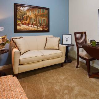 A cozy living room with a cream-colored sofa, a small round table, and wall artwork.