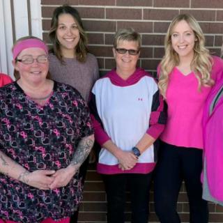 A group of women standing in front of a brick wall, smiling for the camera.