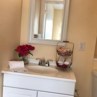 A neatly arranged bathroom with a white vanity, decorative flowers, and a mirror.