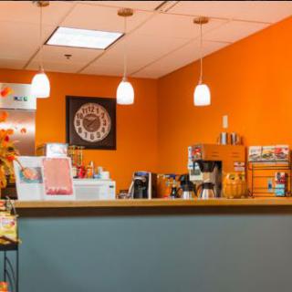 A vibrant and modern cafe interior featuring bright orange walls and a welcoming counter area.