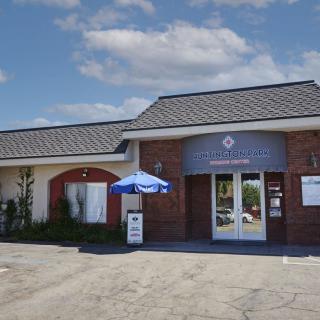 A restaurant building with a blue umbrella outside on a sunny day.