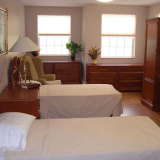 A cozy bedroom with two twin beds, a dresser, and a comfortable chair.