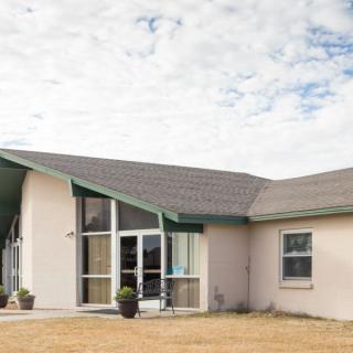 A suburban house with a sloped roof and front yard under a cloudy sky.