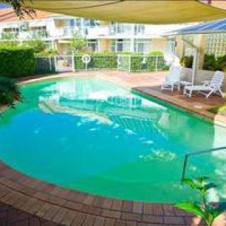 A serene outdoor swimming pool area with lounge chairs and sunshades in a residential setting.