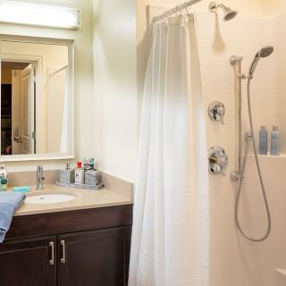 A clean and modern bathroom with a shower, sink, and mirror.