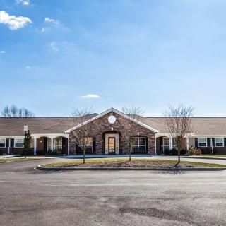 A sunny day view of a commercial building with a large parking lot in front.