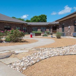 A courtyard with pathways surrounded by landscaped gardens and brick buildings.