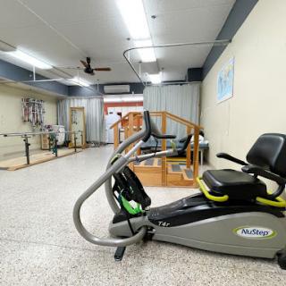 A well-equipped rehabilitation gym featuring exercise machines and a spacious area for physical therapy.