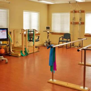 A rehabilitation room equipped with parallel bars and exercise equipment.