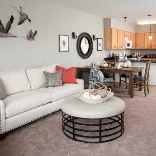 A modern living room with a cozy sofa, stylish coffee table, and an adjacent dining area leading to the kitchen.