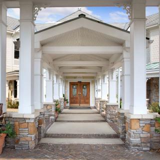 A symmetrical entrance featuring columns and a portico leading to the main doors of a building.