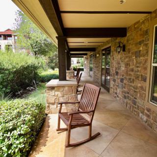 A peaceful outdoor porch with rocking chairs and a stone wall.
