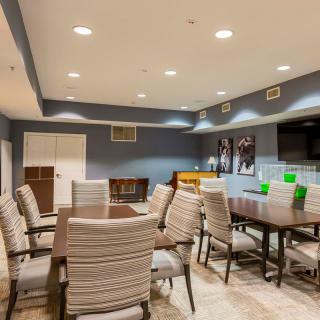 A modern conference room with a large table surrounded by cushioned chairs and ample overhead lighting.