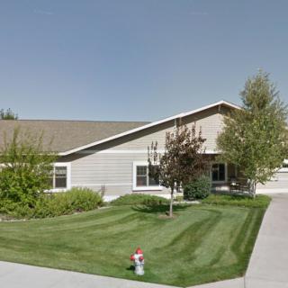 A suburban house with well-maintained landscaping, featuring trees and a grass lawn.