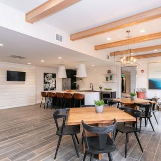 A modern open-plan kitchen and dining area with wooden beams, bar stools, and a stylish chandelier.