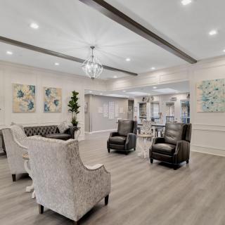 A modern living room with elegant furniture and decor, featuring a chandelier and artwork.