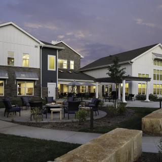 A modern building with outdoor seating illuminated in the evening.